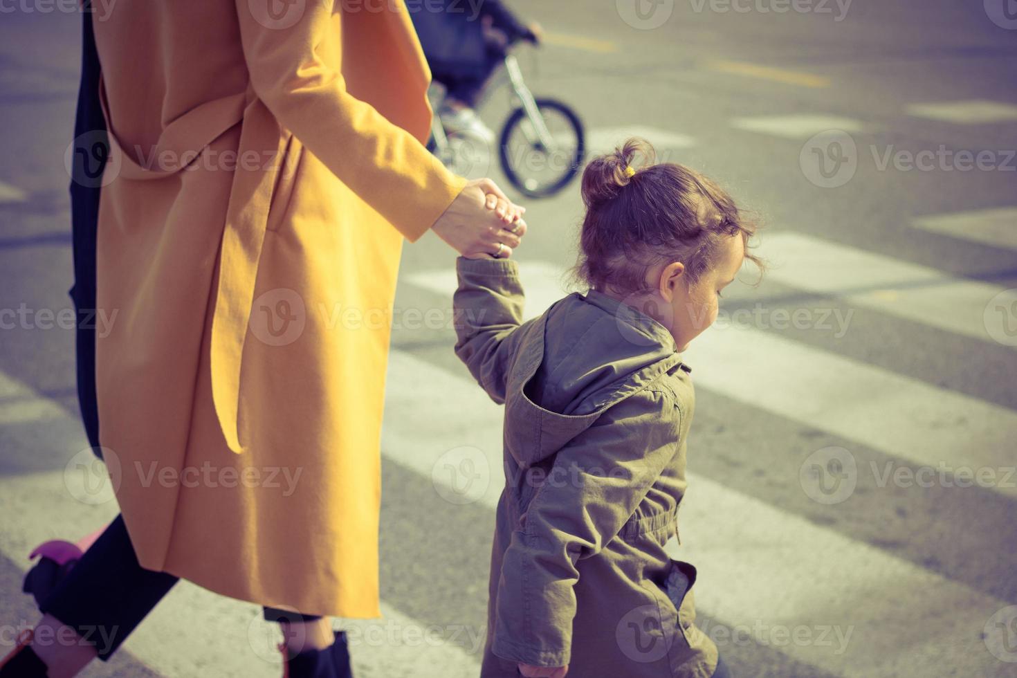 Little girl crossing the street with mother. photo