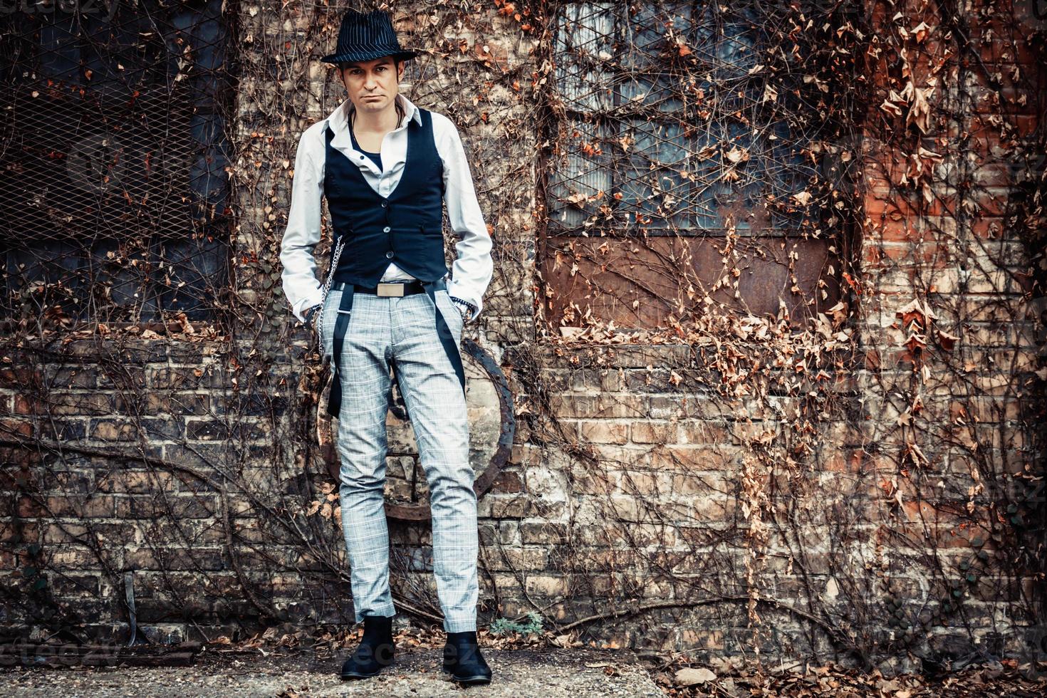 Full length of retro-styled man with a hat against brick wall. photo