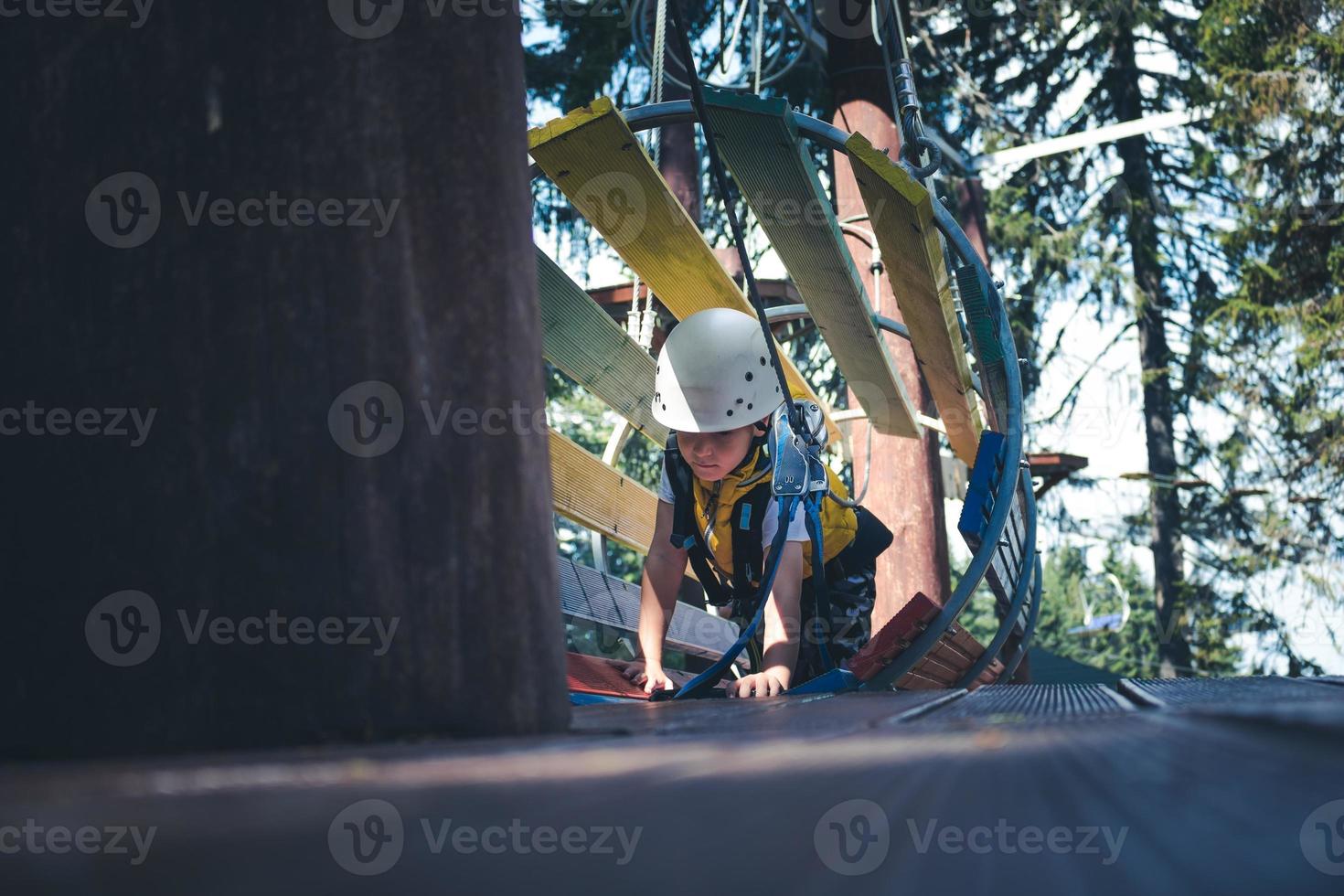 Small kid crawling through obstacles during rope course in nature. photo