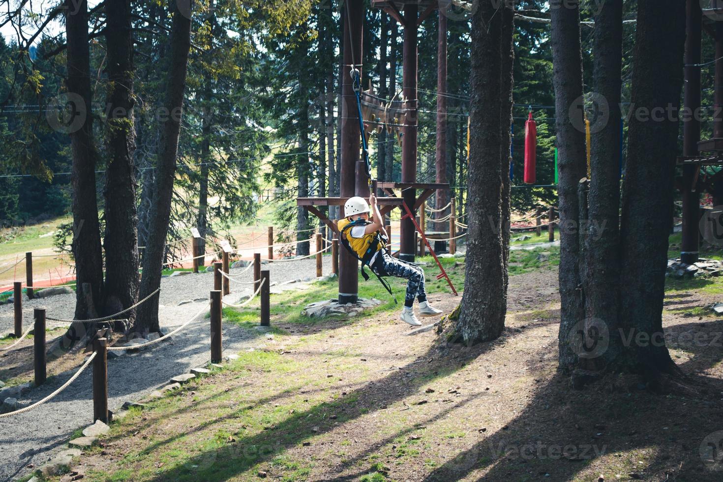 Happy kid having fun while zip lining  in adventure park. photo