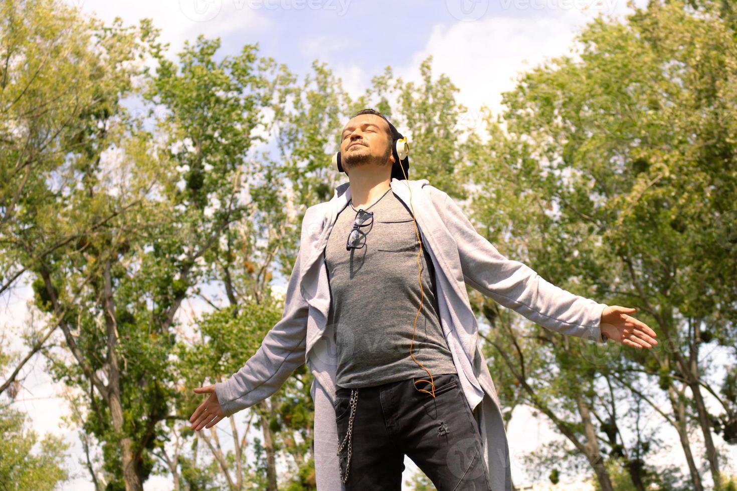 Below view of carefree man enjoying in fresh air with arms outstretched in nature. photo