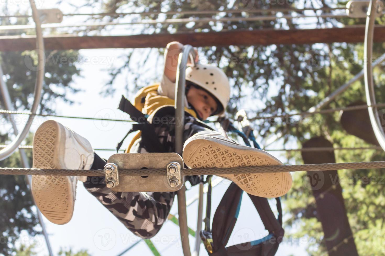 Below view of child getting through obstacles while walking on zip line. photo