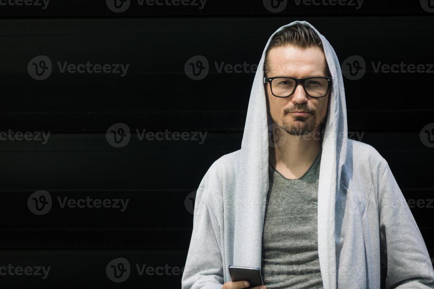 Portrait of man in hooded jacket against black wall. photo