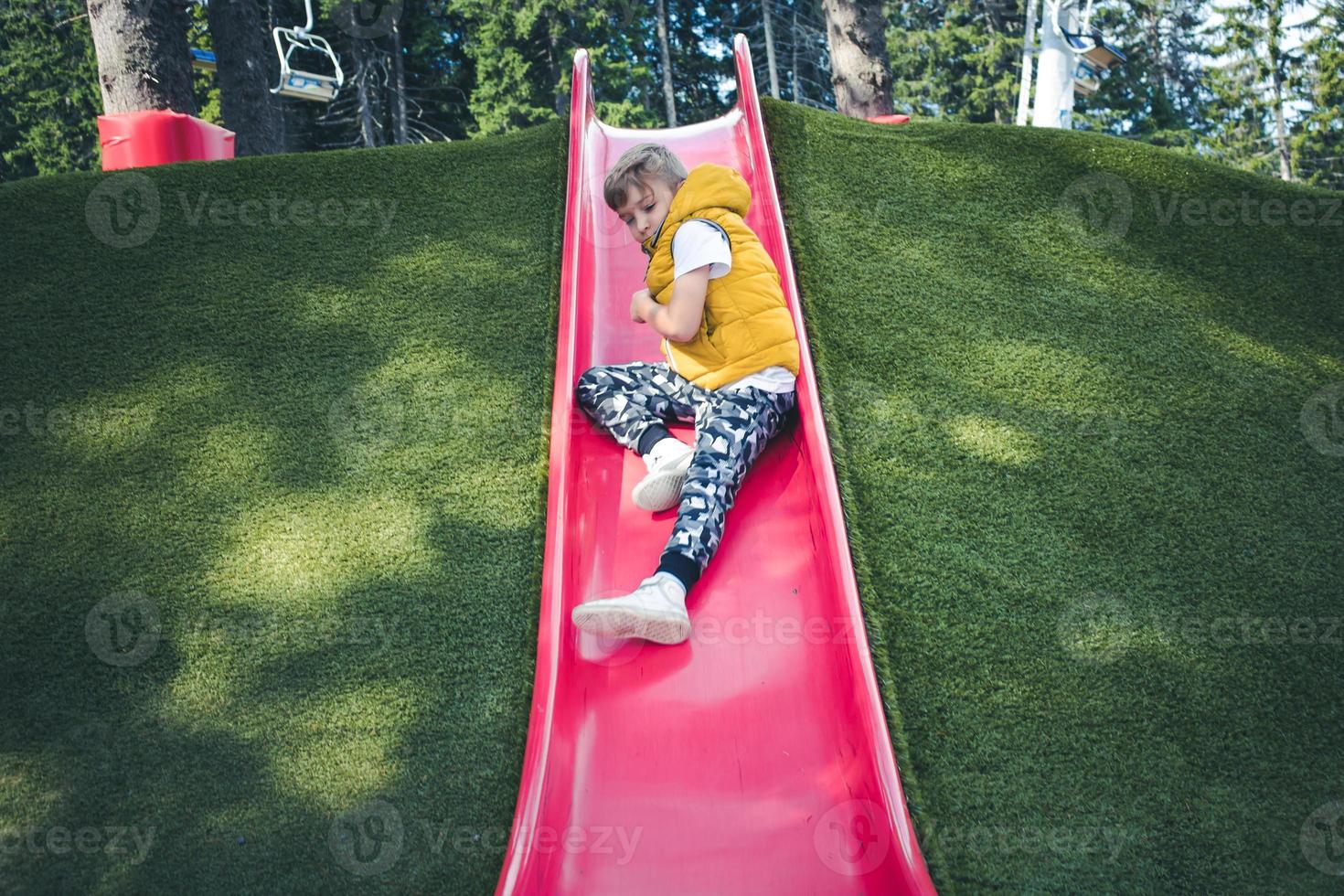 niño deslizándose en el patio de recreo. foto