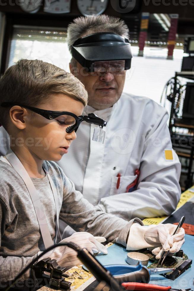 Little boy repairing computer part during IT lesson in science laboratory. photo