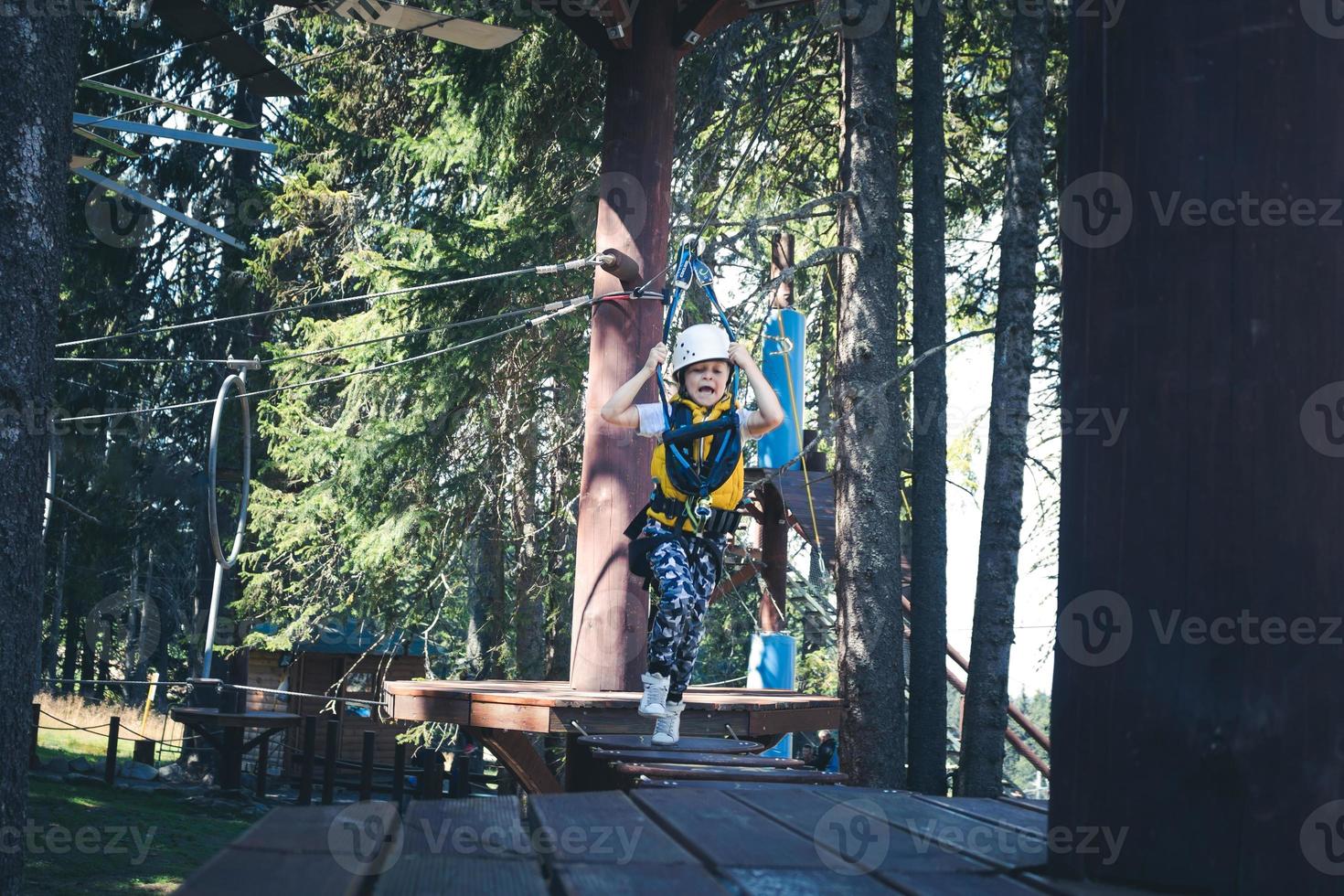 Playful kid crossing over hanging rope during canopy tour. photo