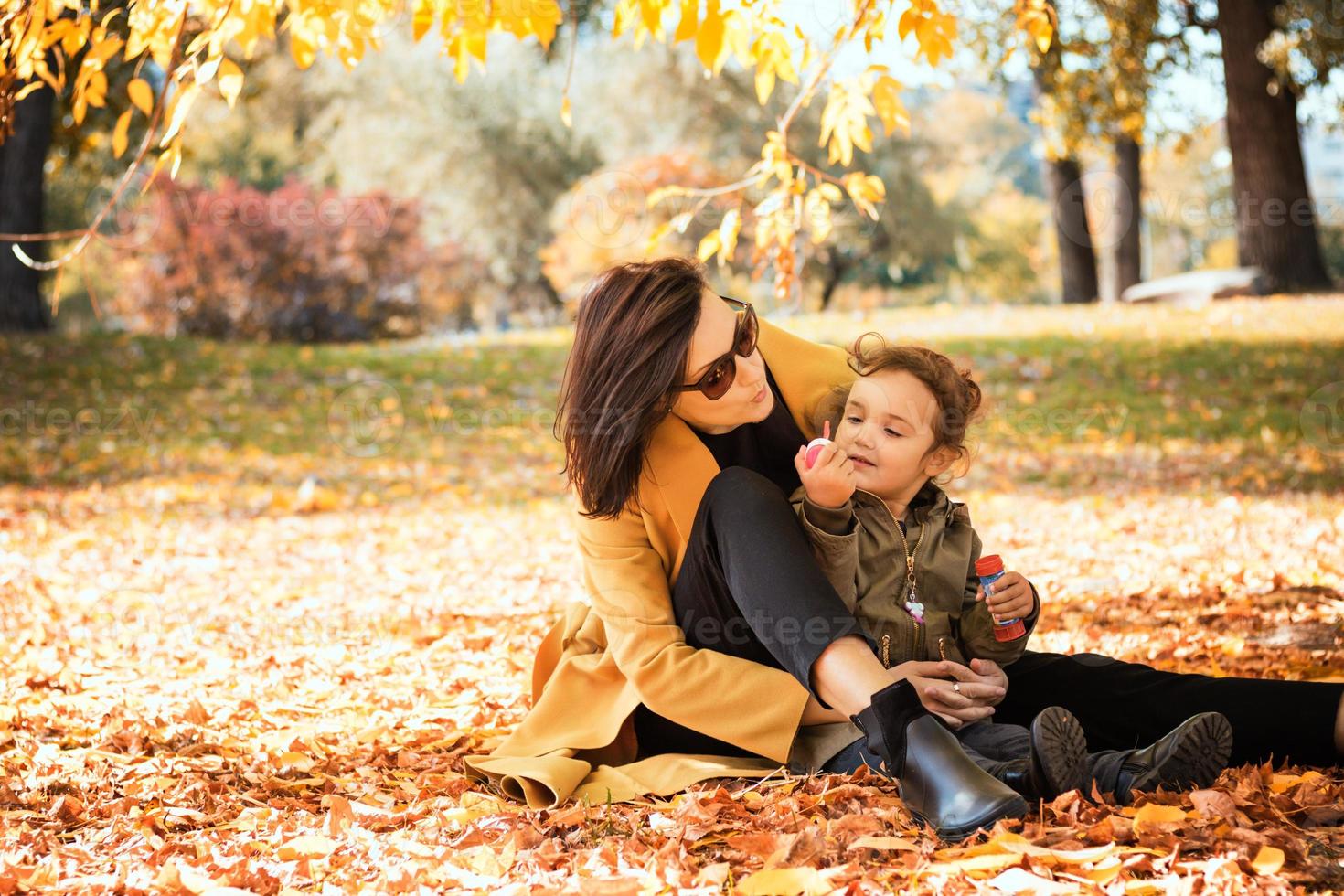 Mother and daughter blowing bubbles in autumn day. photo