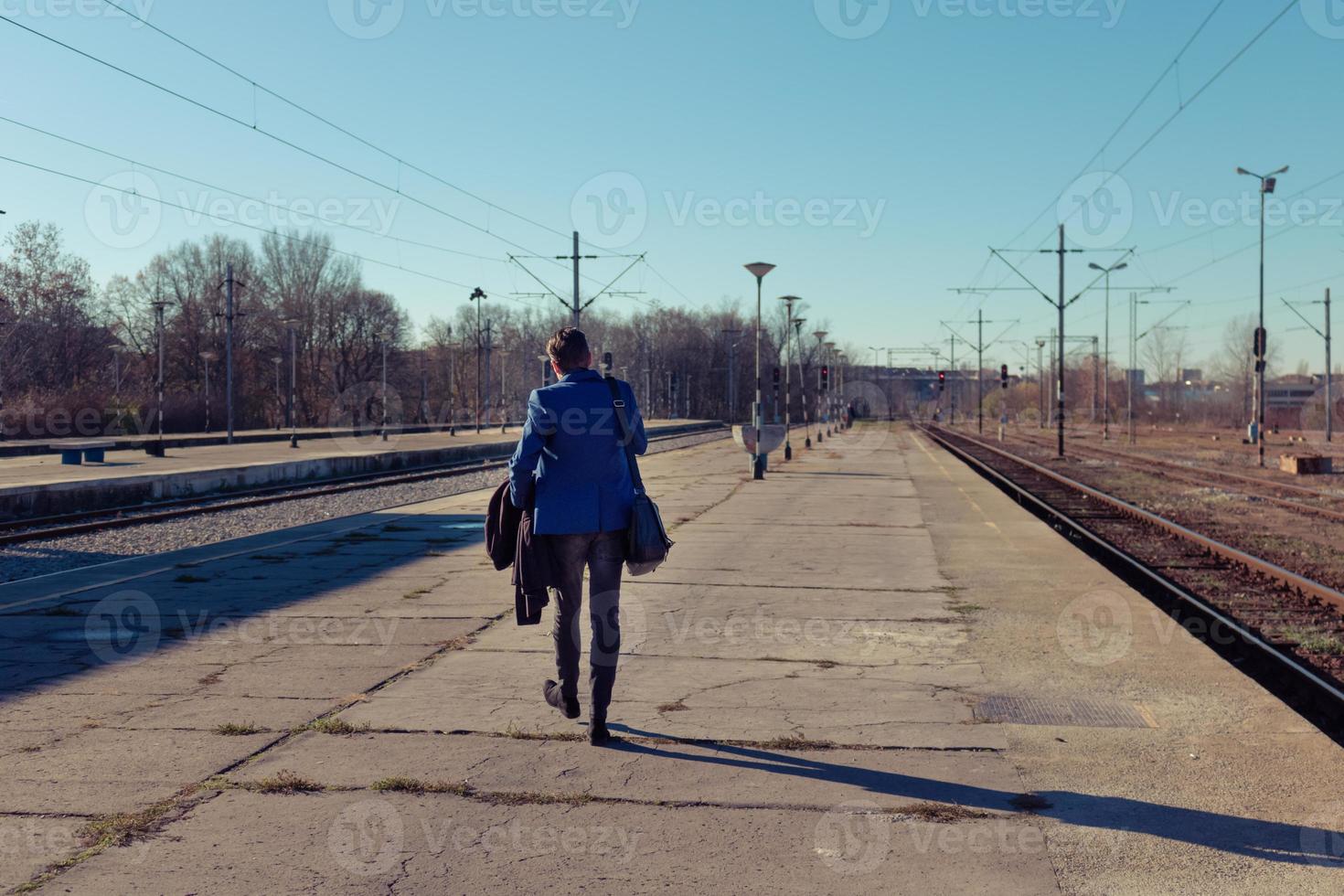 Rear view of man walking at railroad station platform. photo