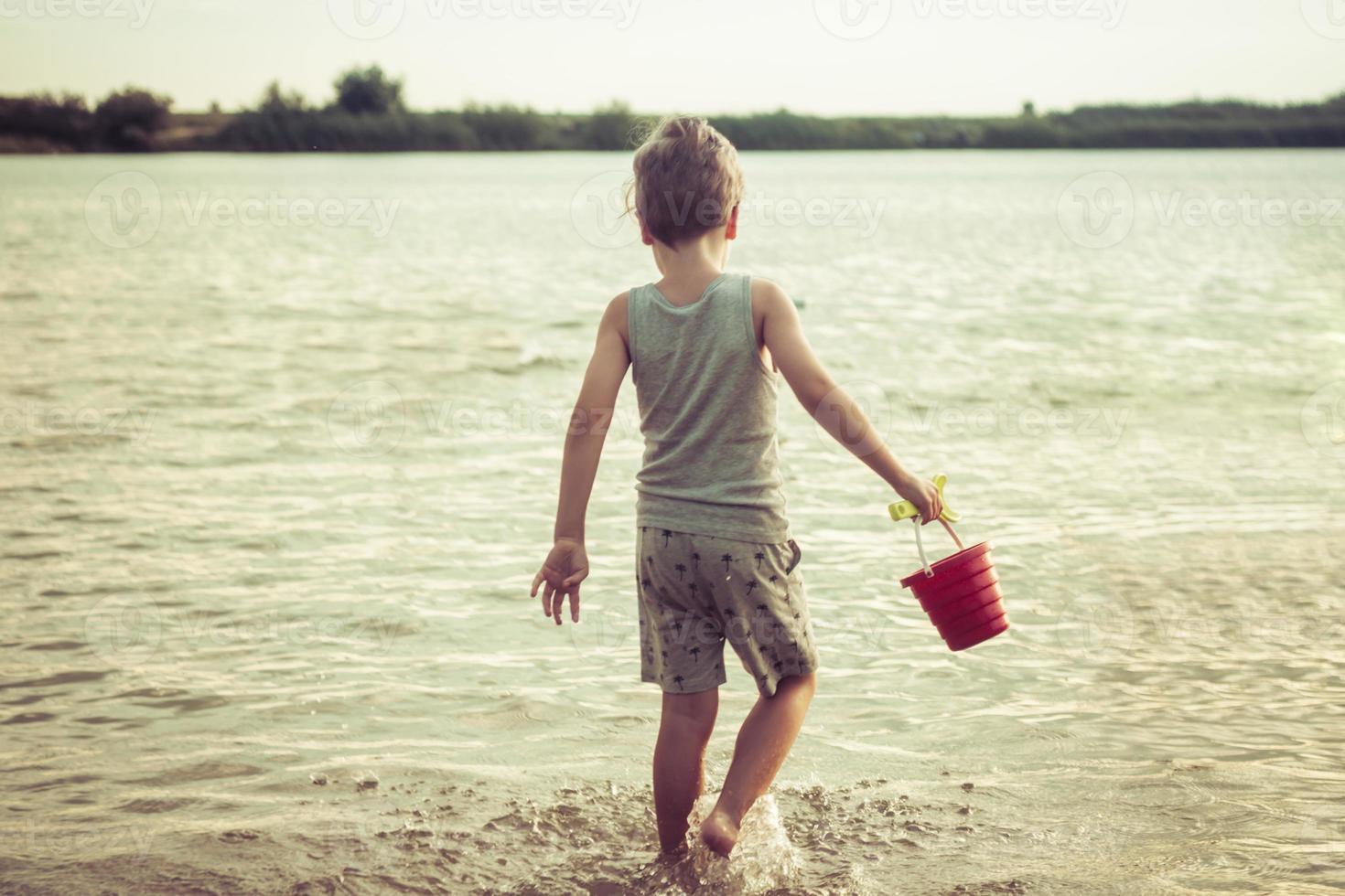 Rear view of boy playing with toys at the beach. photo