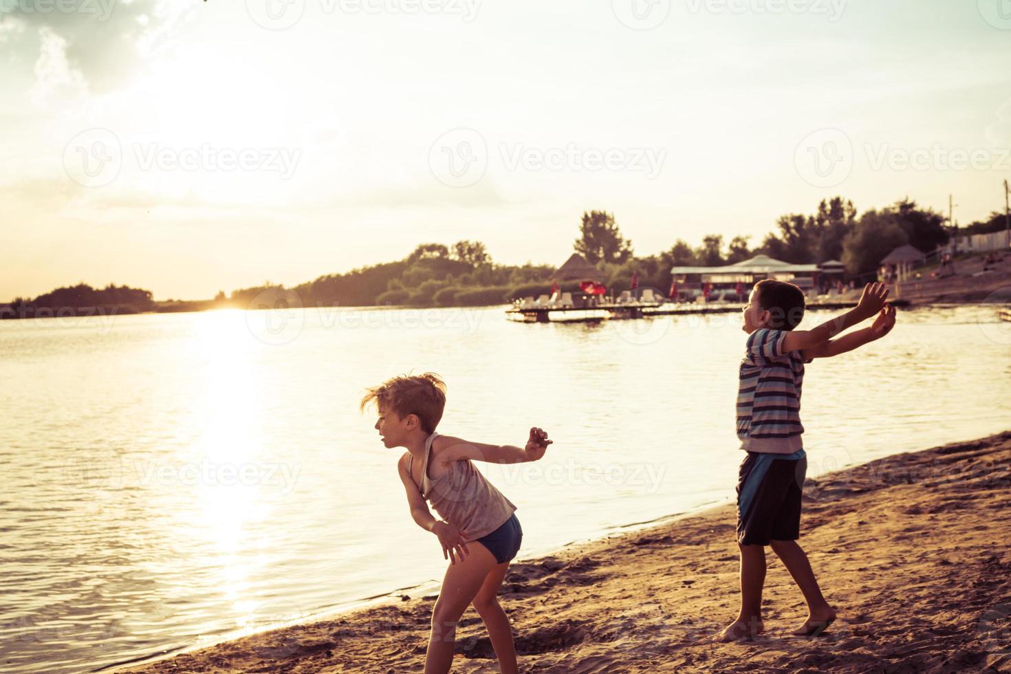 chicos juguetones divirtiéndose en la playa al atardecer. foto