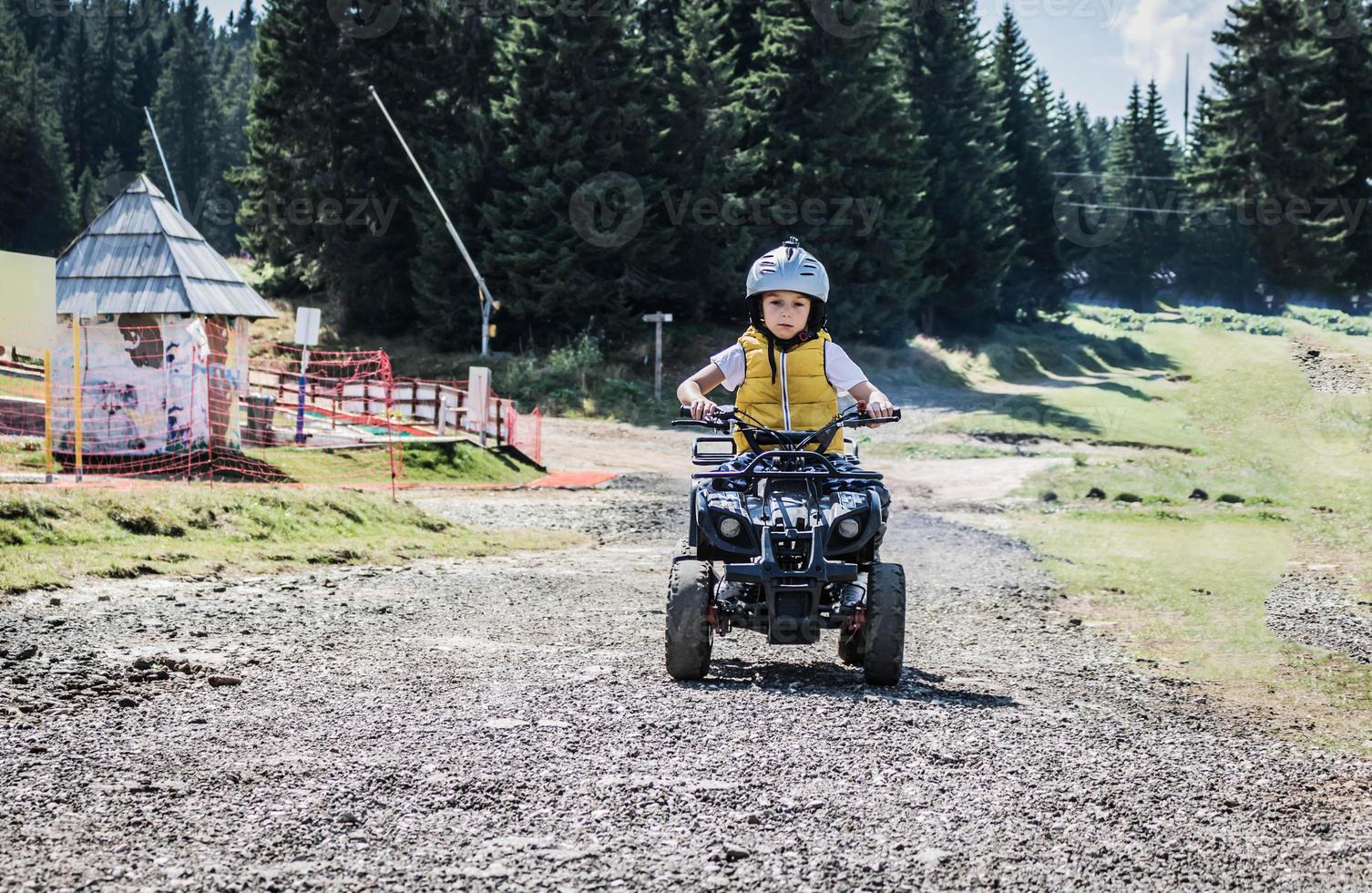 Skilled boy driving atv quad bike on off-road track. photo