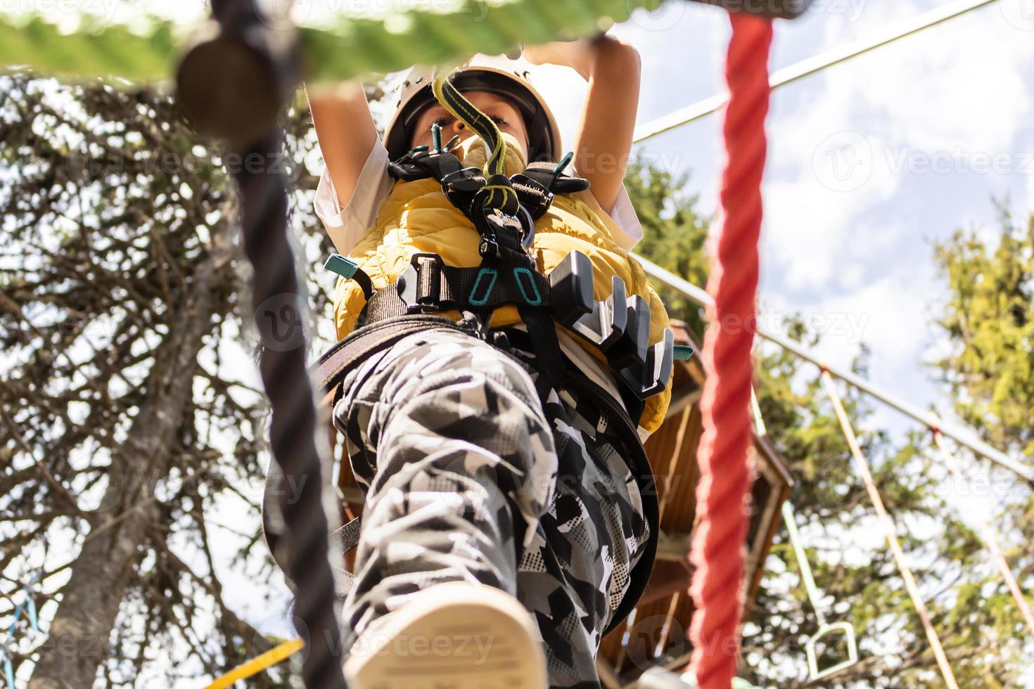 Below view of kid walking on zip line and crossing the obstacles on canopy tour. photo