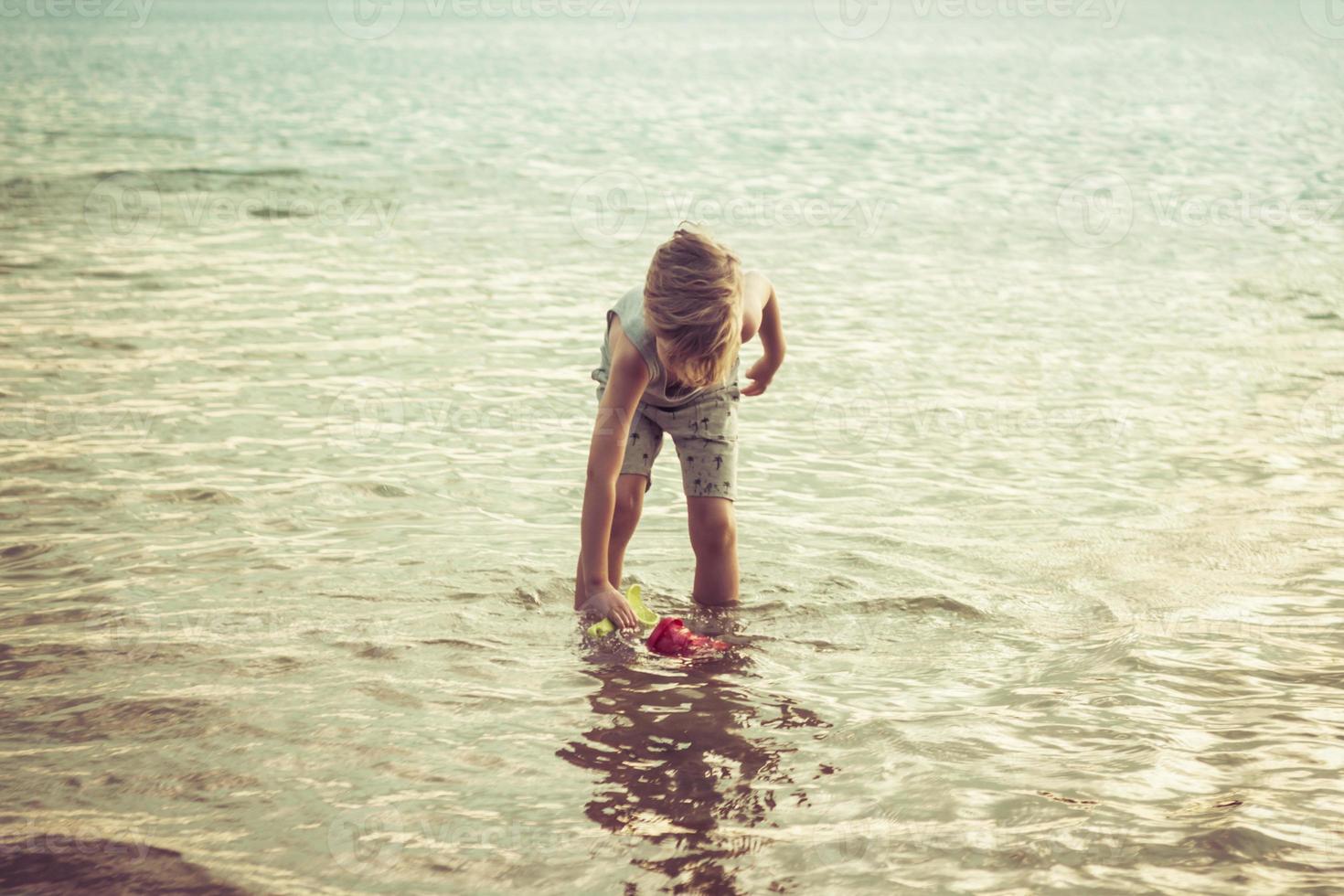 niño pequeño jugando en el agua durante el día de verano. foto