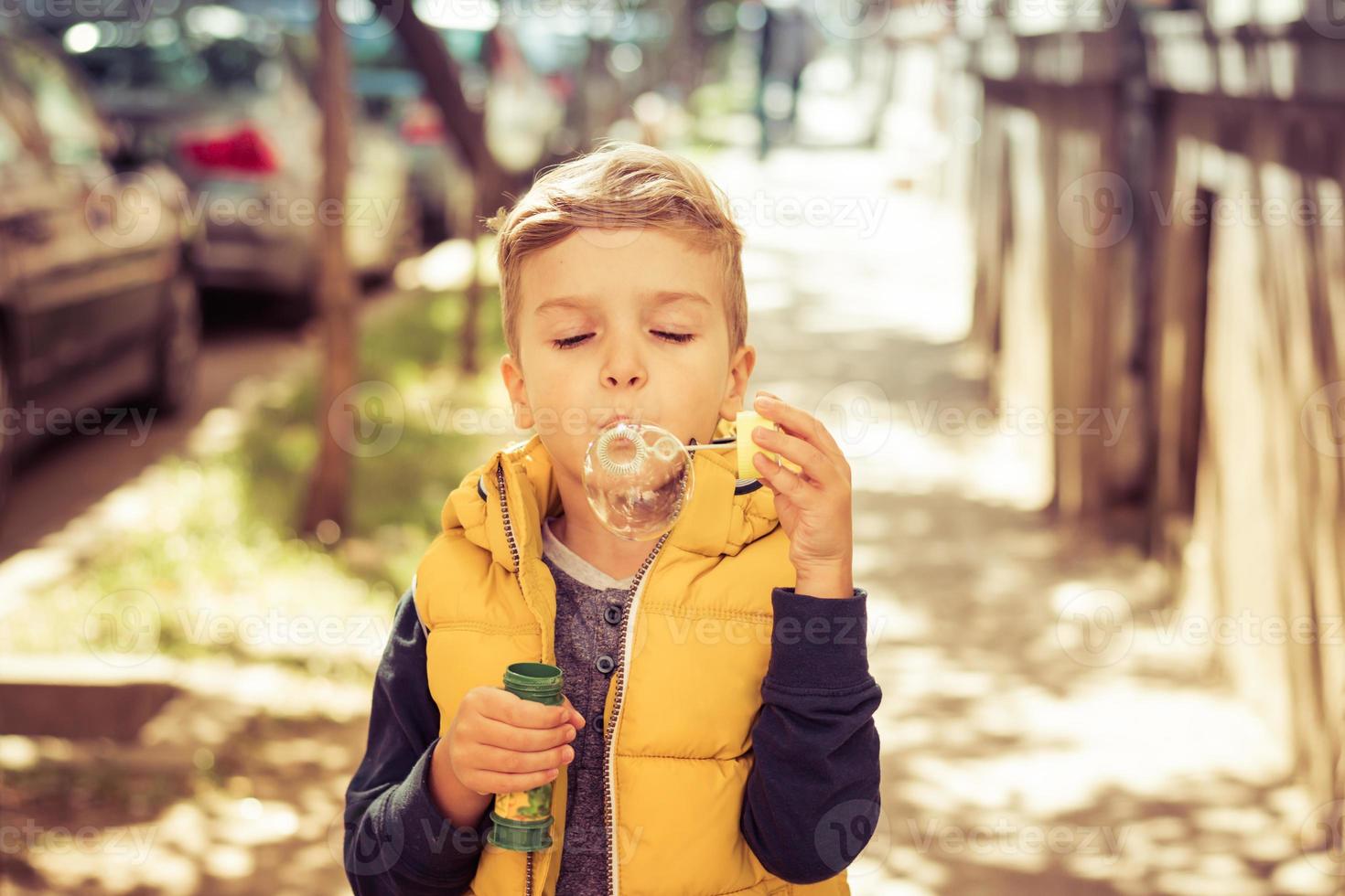 Small boy blowing bubbles outdoors. photo