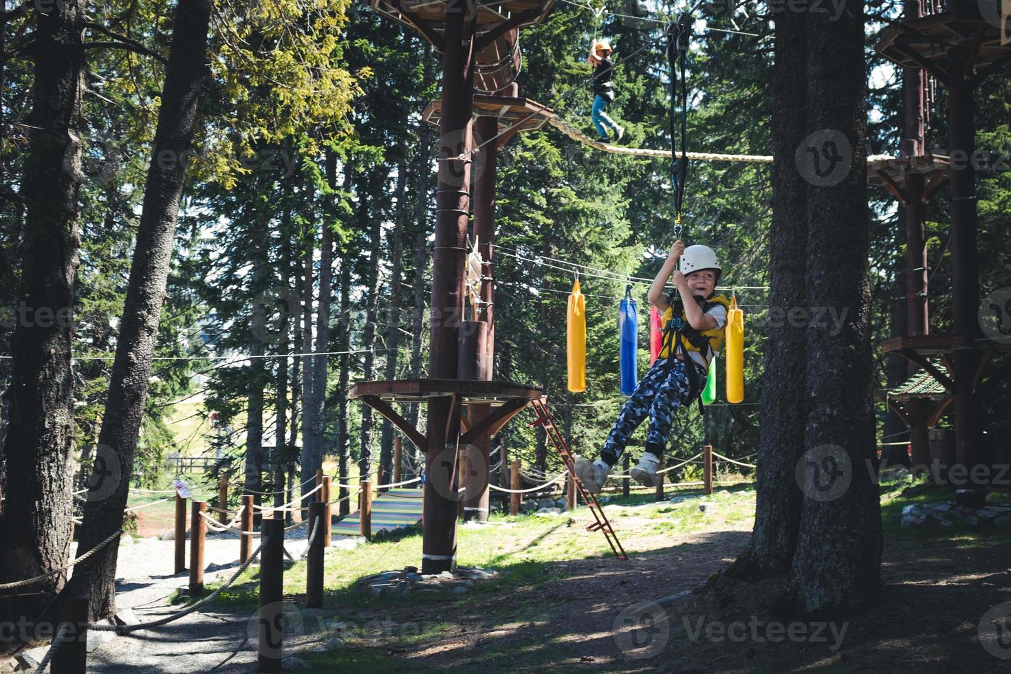 Happy kid zip-lining in the forest. photo