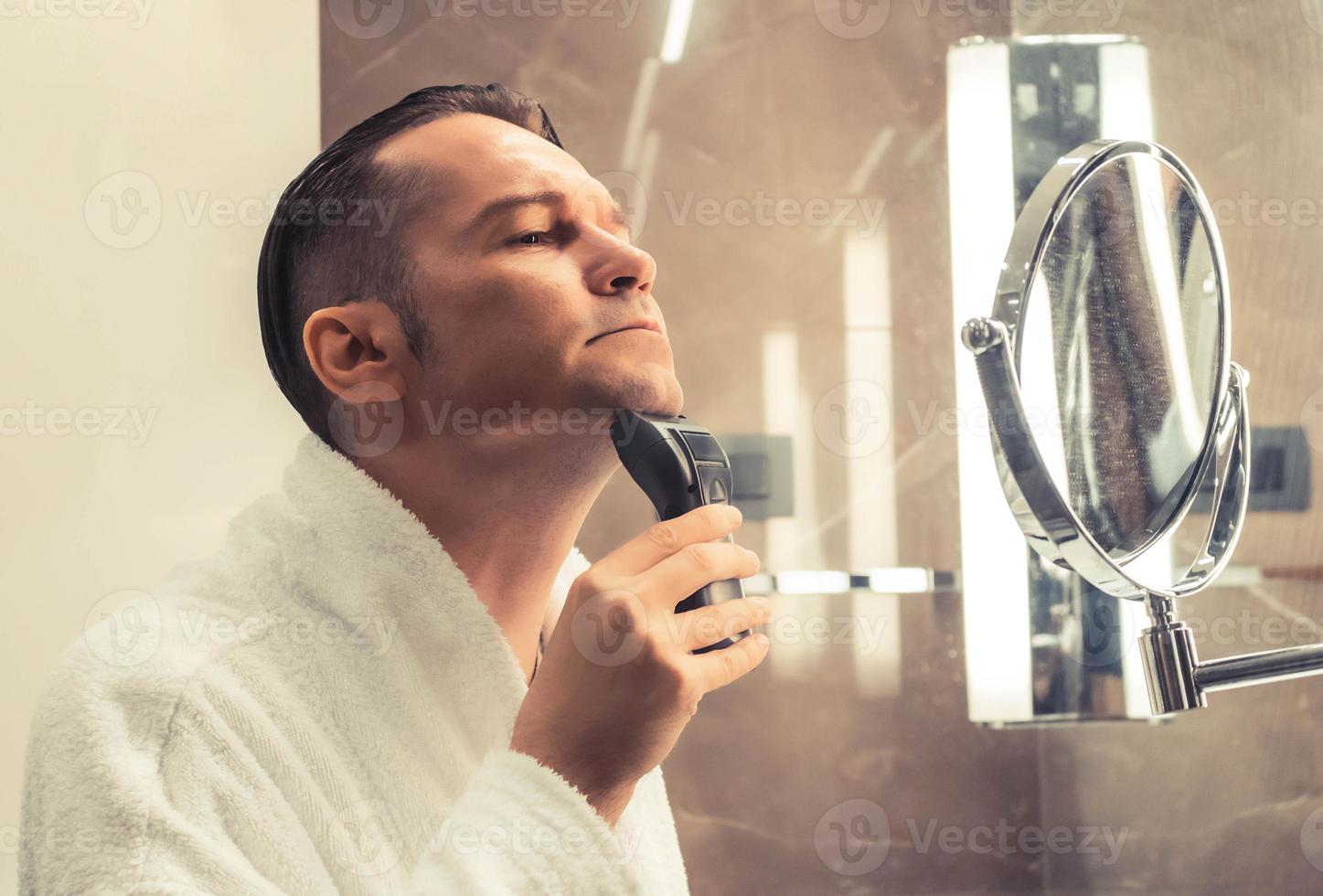 Mid adult man shaving with electric razor. 10910186 Stock Photo at Vecteezy