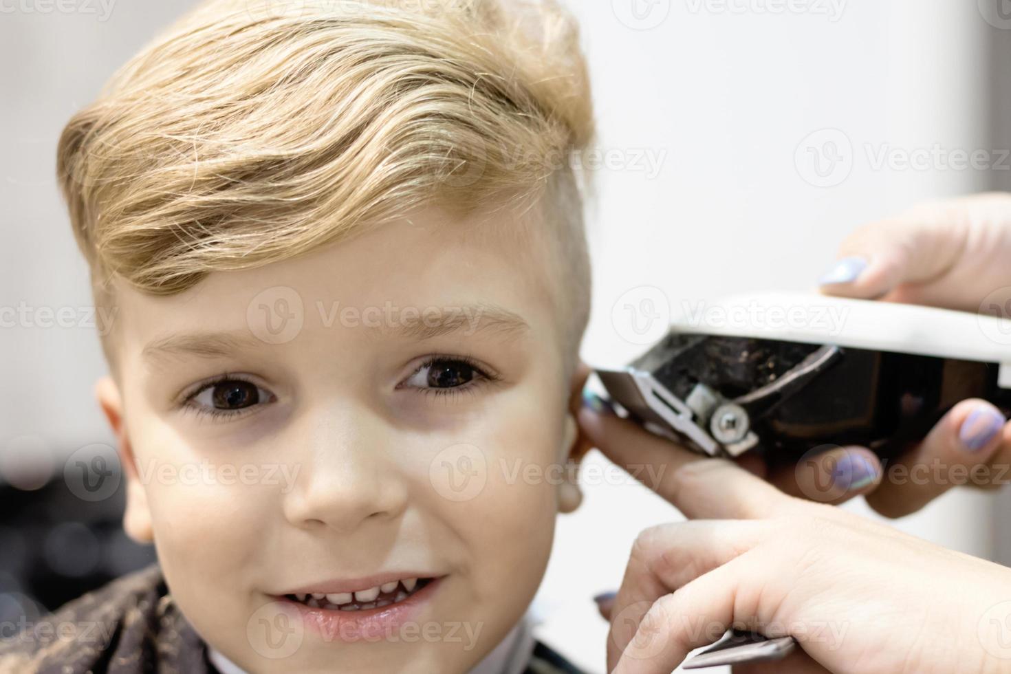 primer plano de niño durante el corte de pelo en el salón. foto