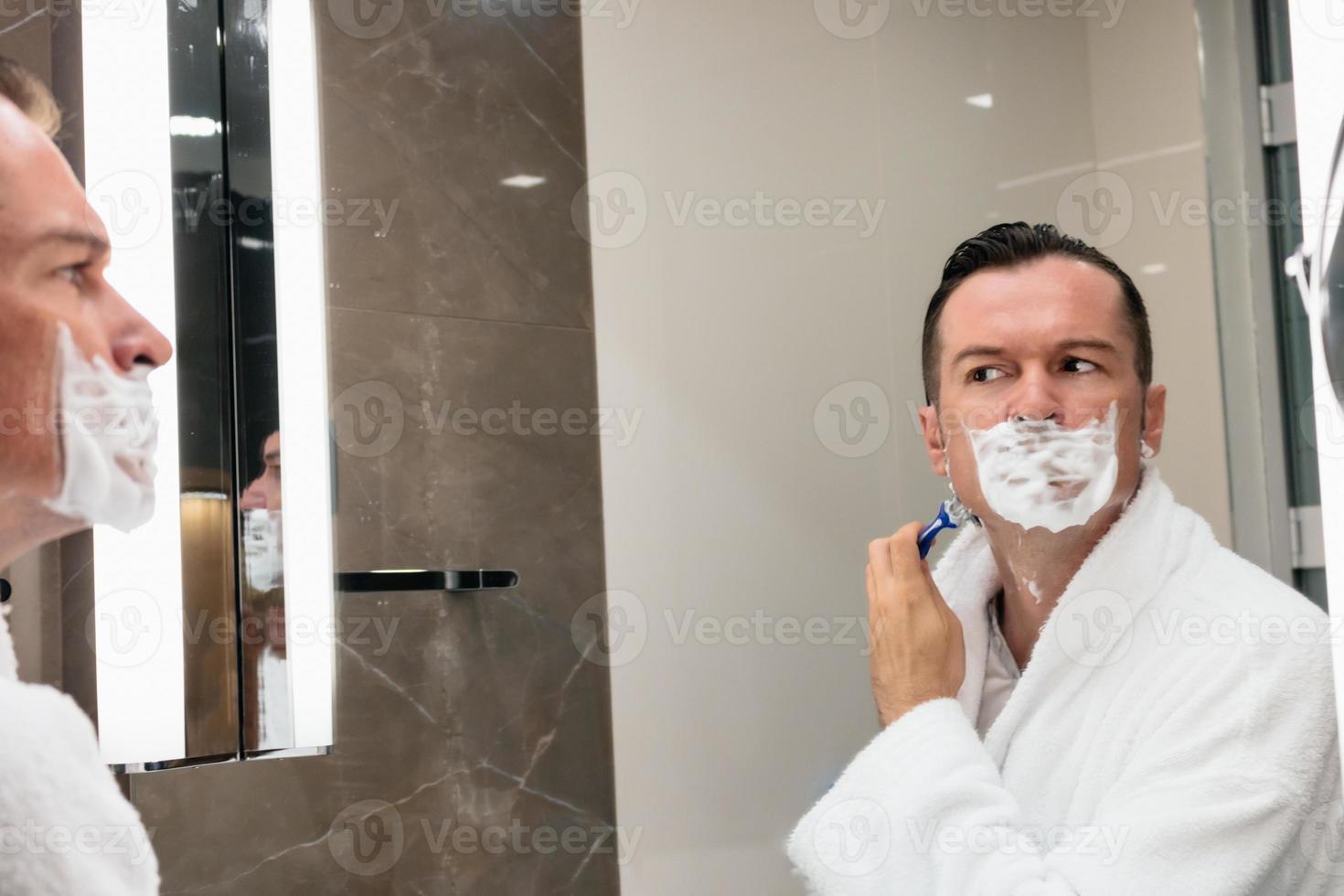 Reflection in the mirror of a man shaving in the bathroom. photo