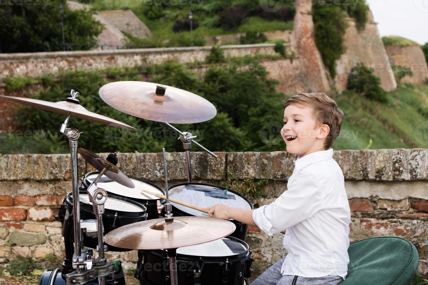 Happy kid playing drums outdoors. photo