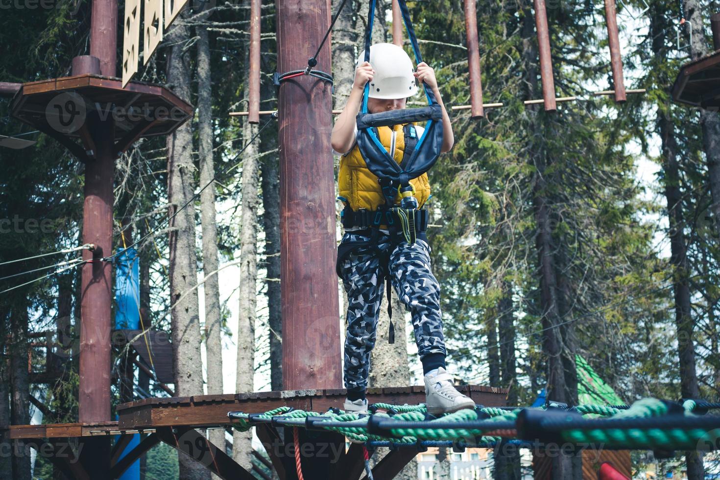 Small boy walking over obstacles during canopy tour in nature. photo