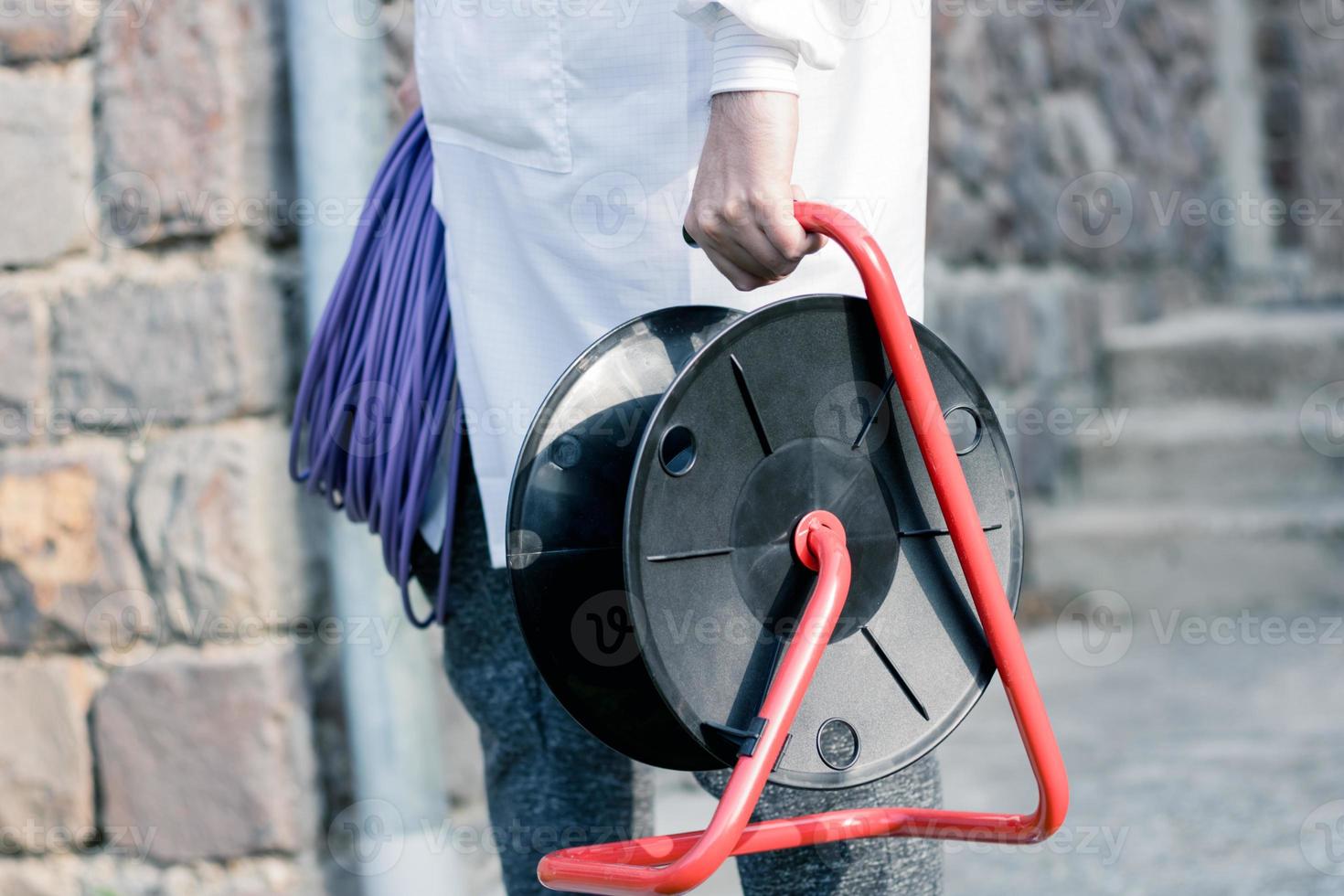 Unrecognizable maintenance worker with power plug reel. photo