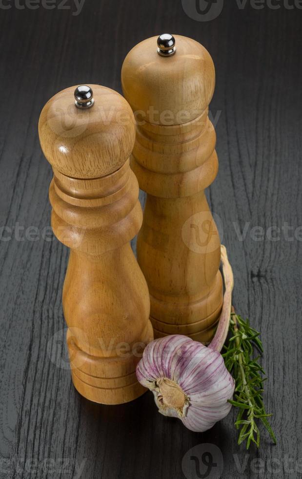 Pepper mill with garlic on wooden background photo