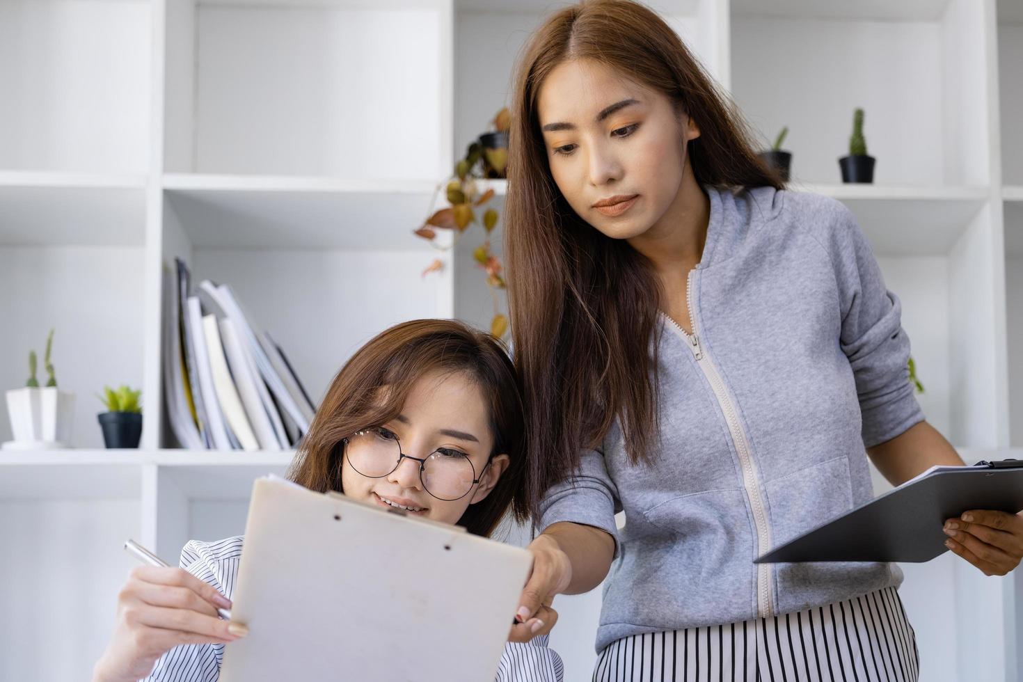 Businesswomen and colleagues are using budget document to calculate last quarter earnings of the year to plan financial investments for the coming year. photo