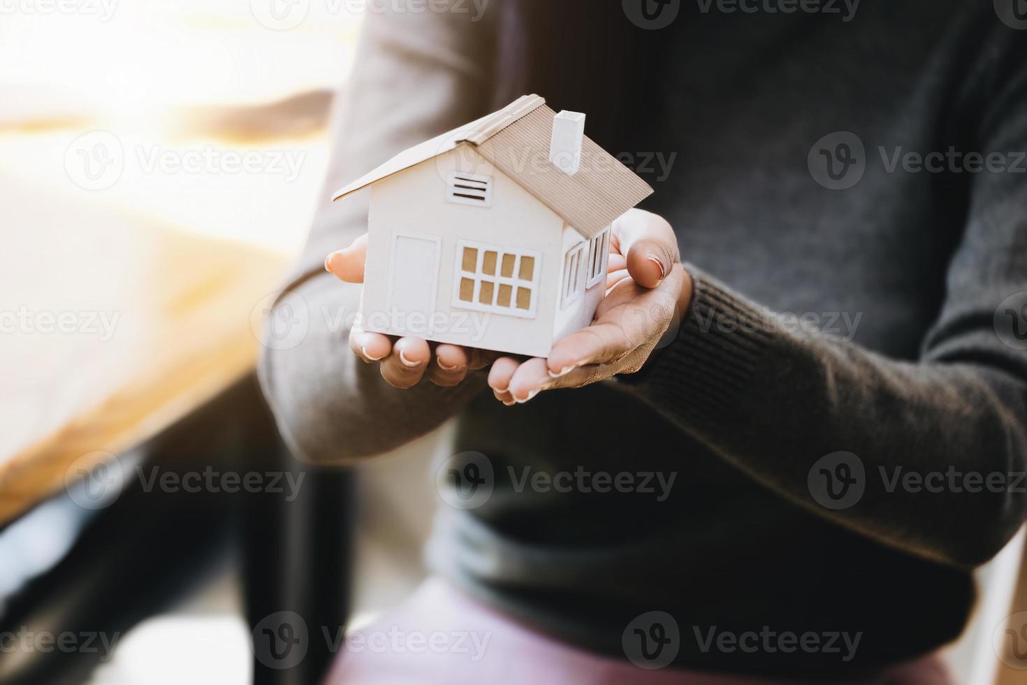 mano femenina sosteniendo un modelo de casa, concepto de seguro y préstamo hipotecario. foto