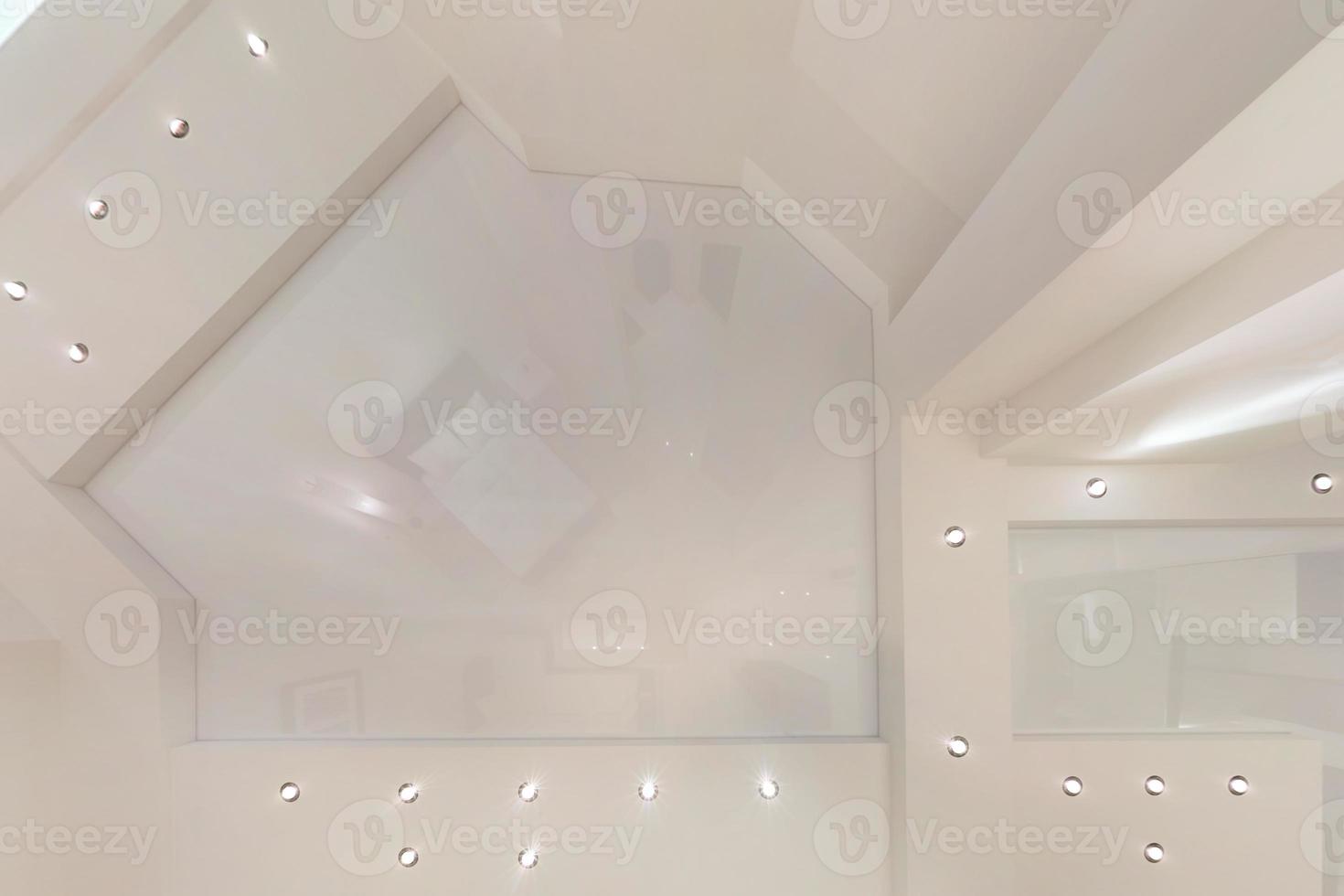 suspended ceiling with halogen spots lamps and drywall construction in empty room in apartment or house. Stretch ceiling white and complex shape. photo