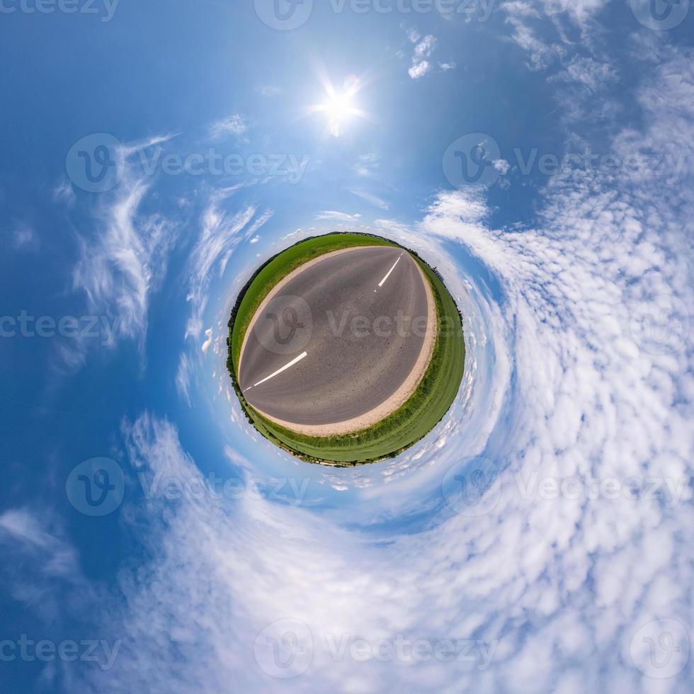 green tiny planet in blue sky with sun and beautiful clouds. Transformation of spherical panorama 360 degrees. Spherical abstract aerial view. Curvature of space. photo