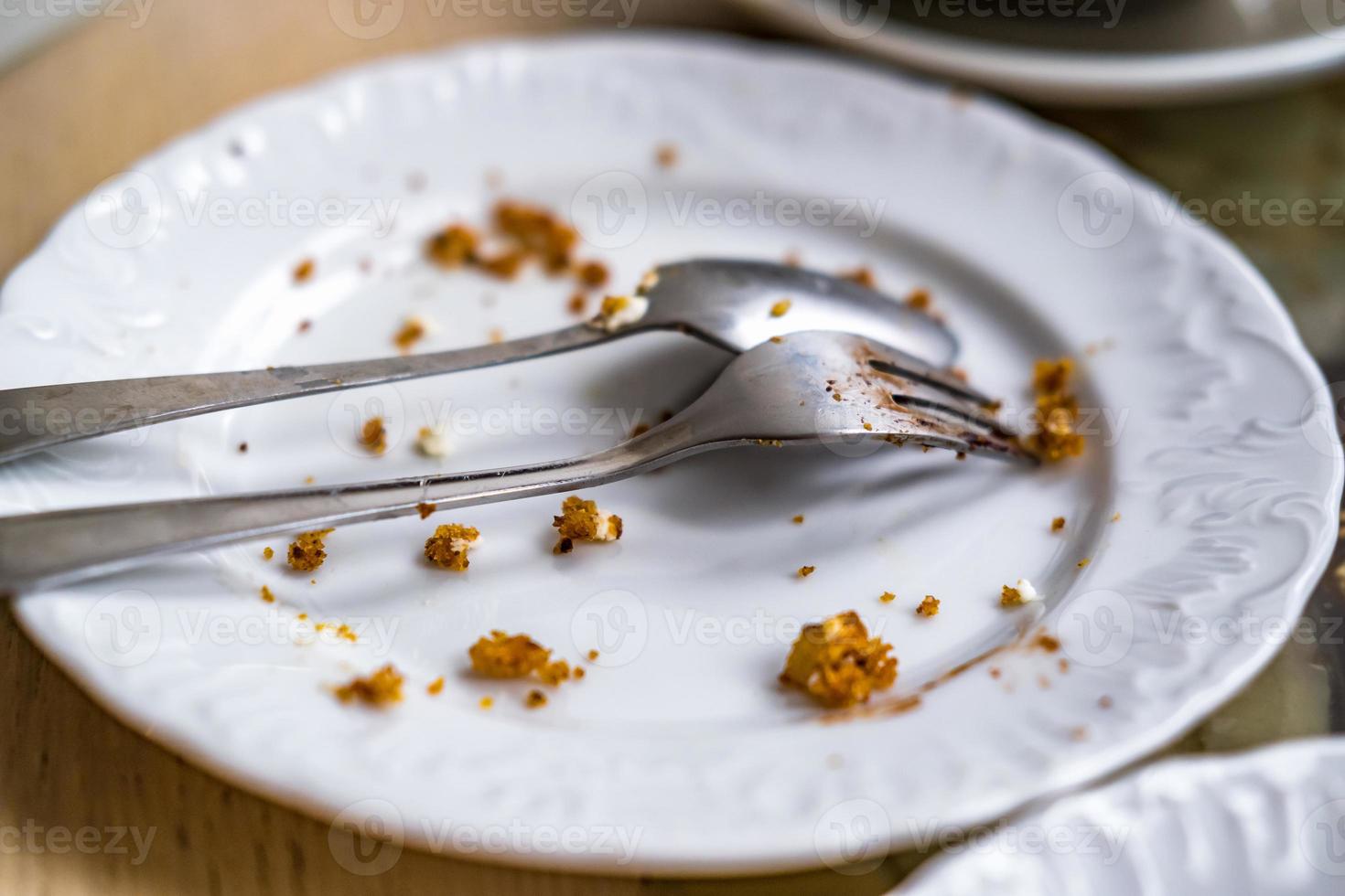 Empty dirty plate with spoon and fork on the table after breakfast photo