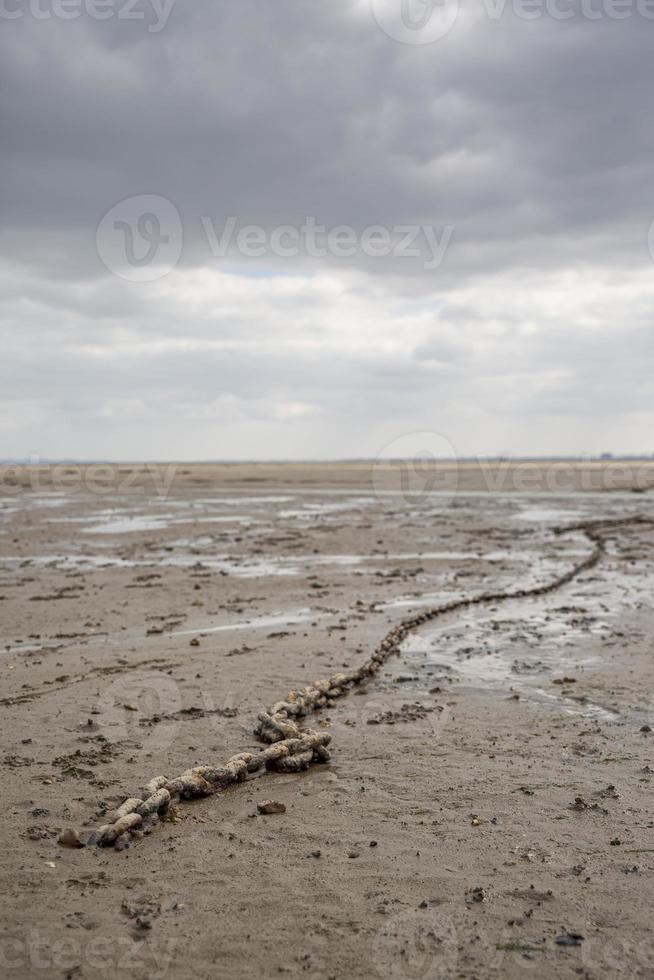 Fishing boat anchor chain stuck on the beach in low tide period. photo