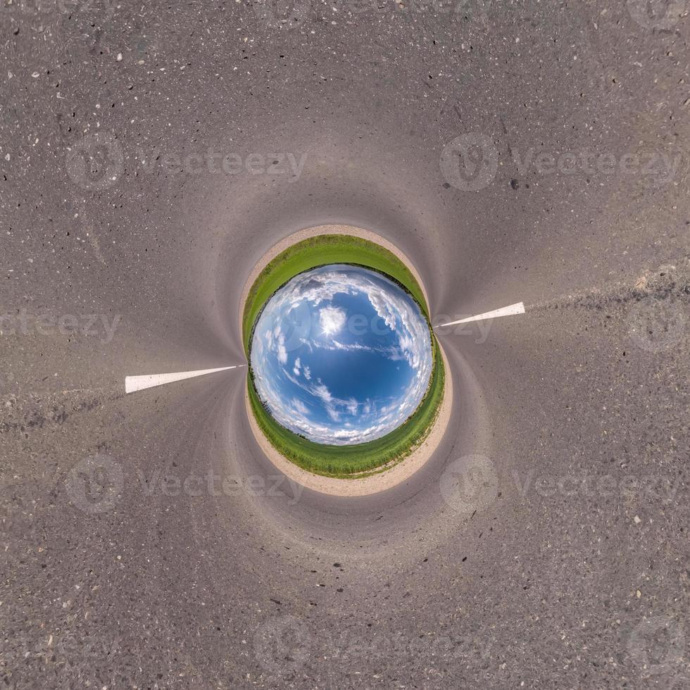 Inversion of blue little planet transformation of spherical panorama 360 degrees. Spherical abstract aerial view on field with awesome beautiful clouds. Curvature of space. photo