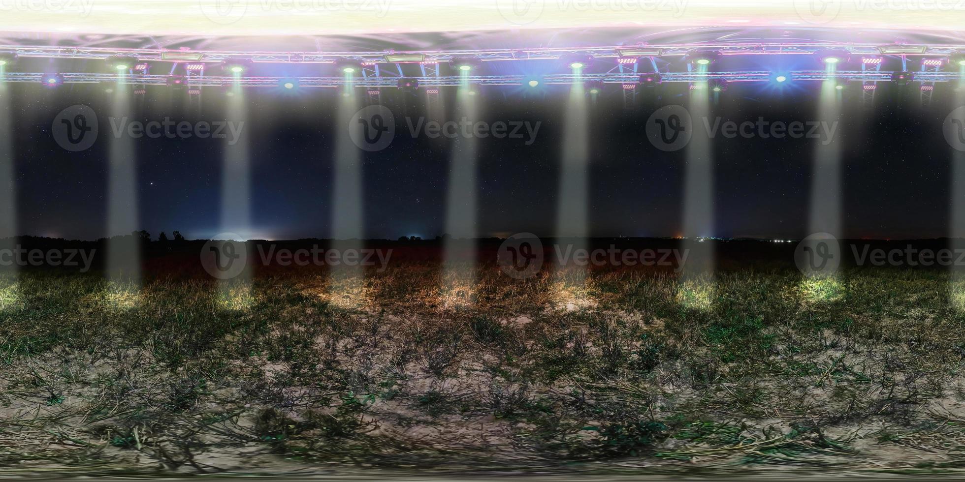 panorama esférico nocturno 360 sin costuras entre campos con platillo volador flotando sobre el suelo con focos fuertes en proyección equirectangular, listo para contenido de realidad virtual vr ar foto