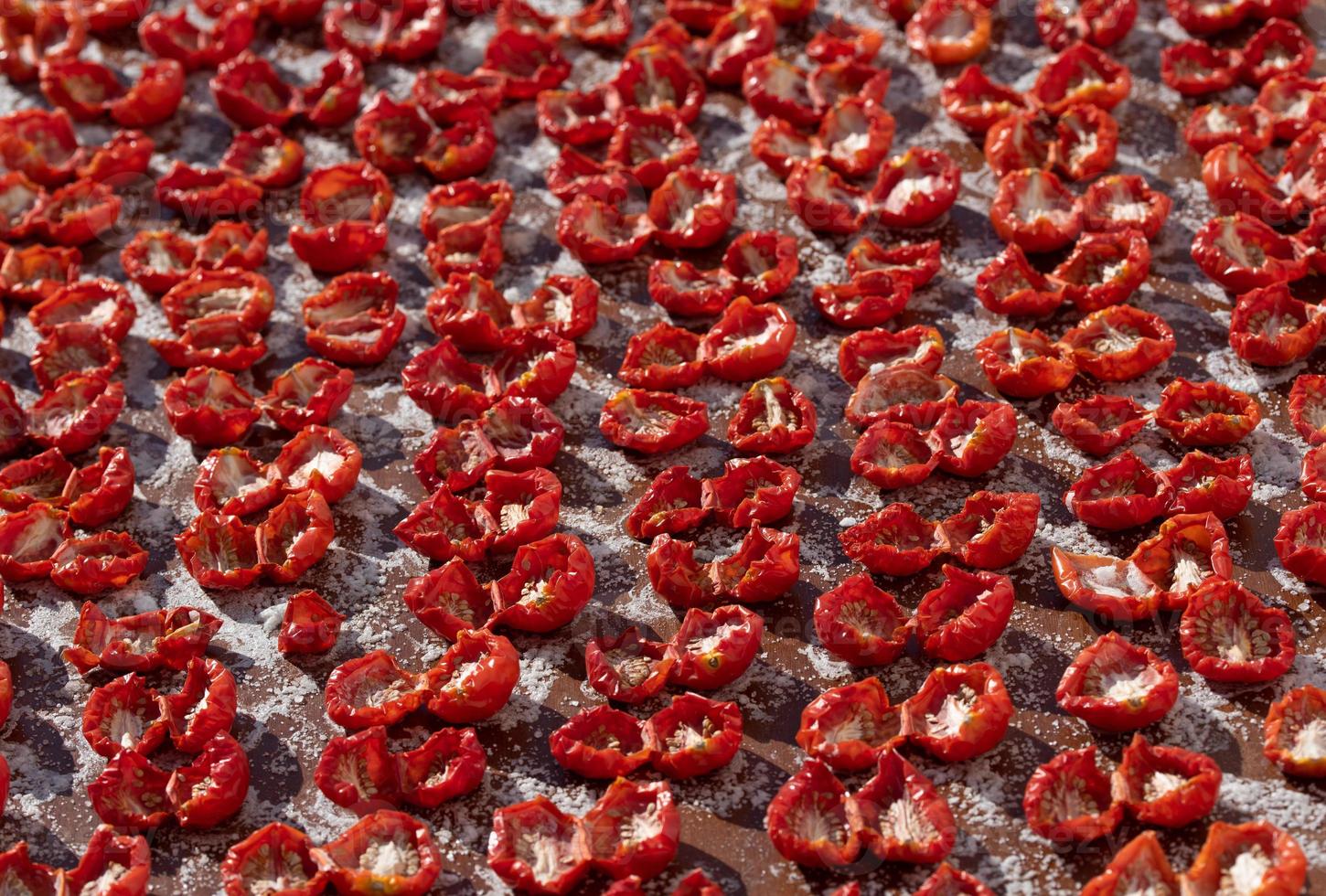 Lots of tomatoes lying next to each other for drying and canning. The tomatoes are salted. photo