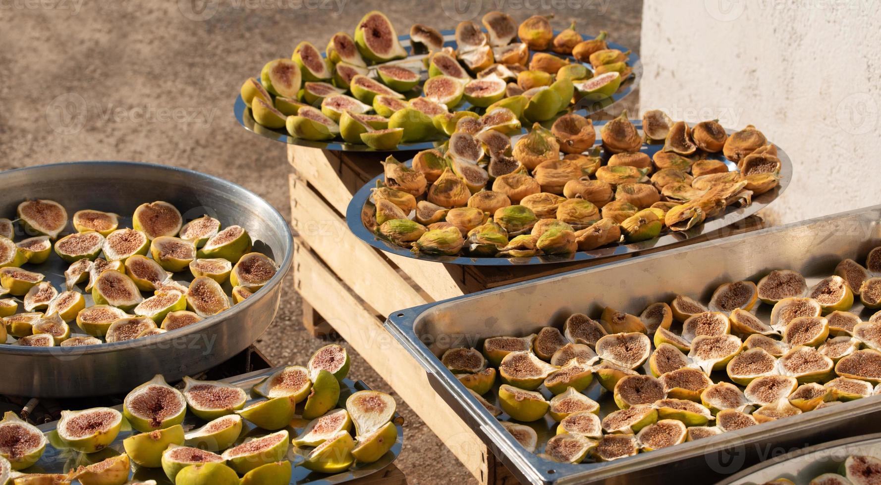 Various figs are lying on various flat bowls to dry in the sun photo