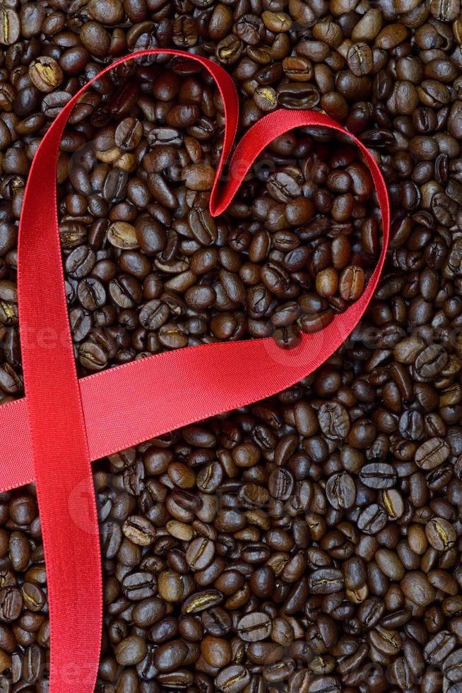 A heart is wound from a red ribbon on dried and roasted brown coffee beans photo