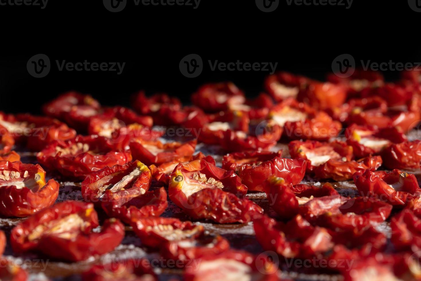 Close up and background of tomatoes lying in the sun to dry. the background is black. photo