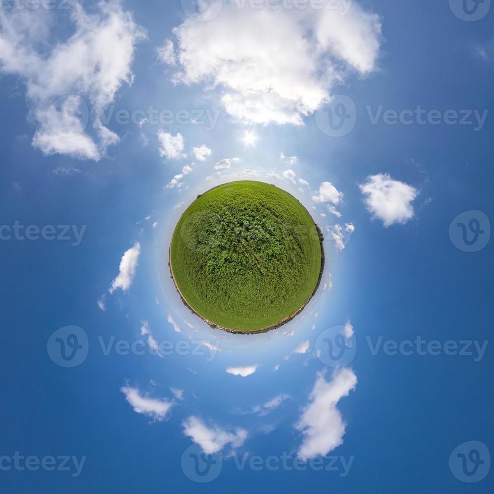 green tiny planet in blue sky with beautiful clouds. Transformation of spherical panorama 360 degrees. Spherical abstract aerial view. Curvature of space. photo
