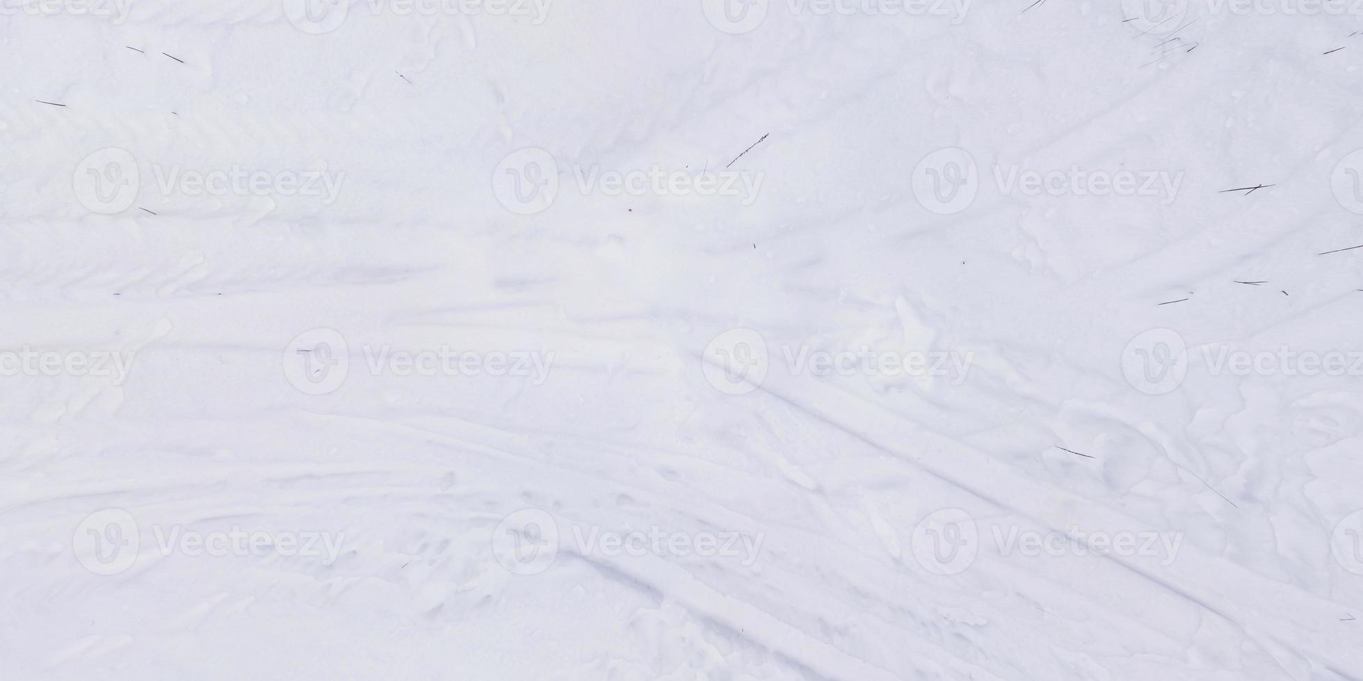 panorama view from above on texture of snow covered road with car tire tracks and footprints photo