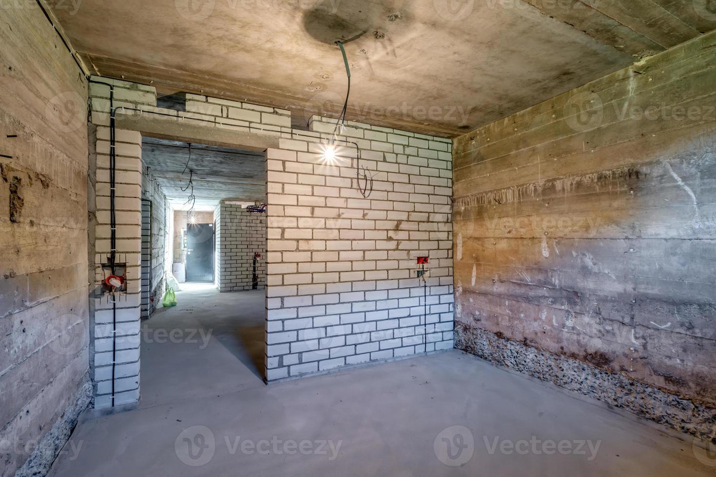 Empty unfurnished basement room with minimal preparatory repairs. interior with white brick walls photo