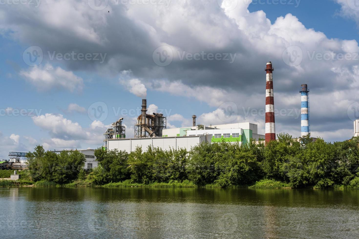 tuberías del aserradero de la planta de la empresa de carpintería cerca del río. concepto de contaminación del aire. paisaje industrial contaminación ambiental residuos de central térmica foto