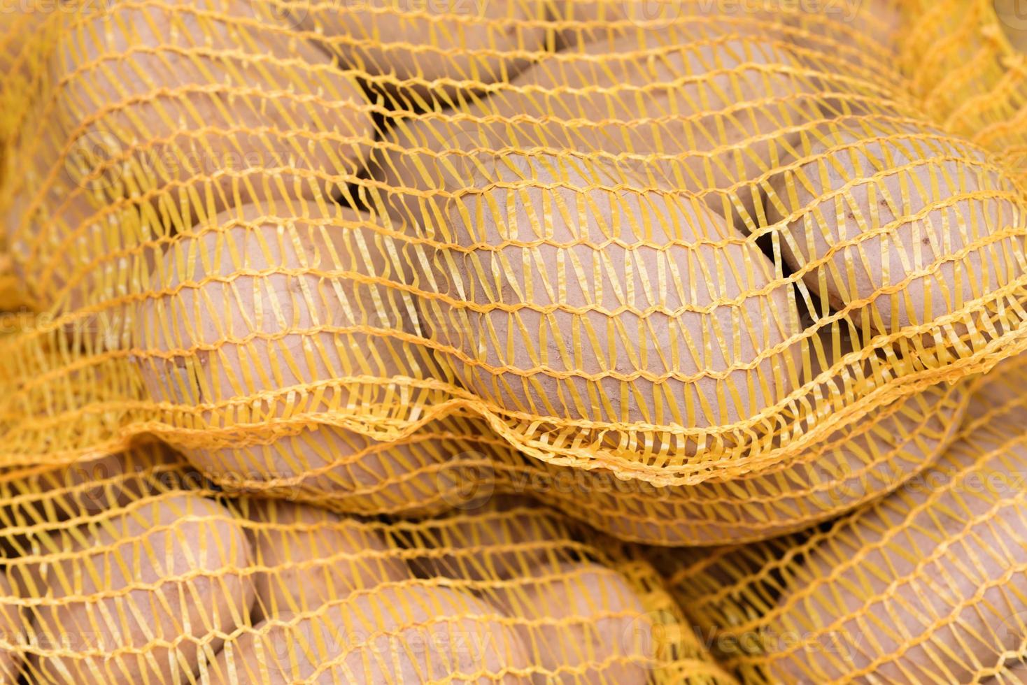 Freshly harvested potatoes in the net are for sale in the market photo