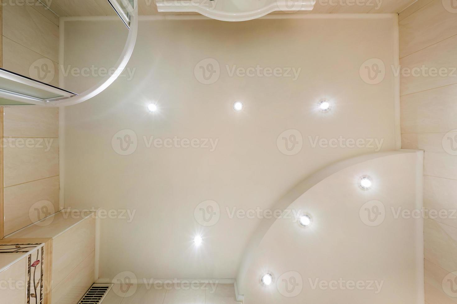 suspended ceiling with halogen spots lamps and drywall construction in empty room in apartment or house. Stretch ceiling white and complex shape. photo