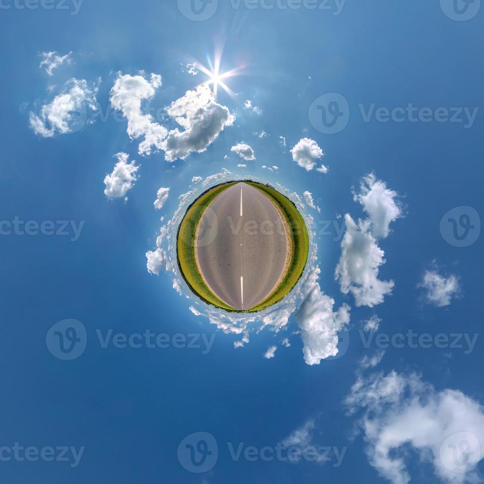 green tiny planet in blue sky with beautiful clouds. Transformation of spherical panorama 360 degrees. Spherical abstract aerial view. Curvature of space. photo