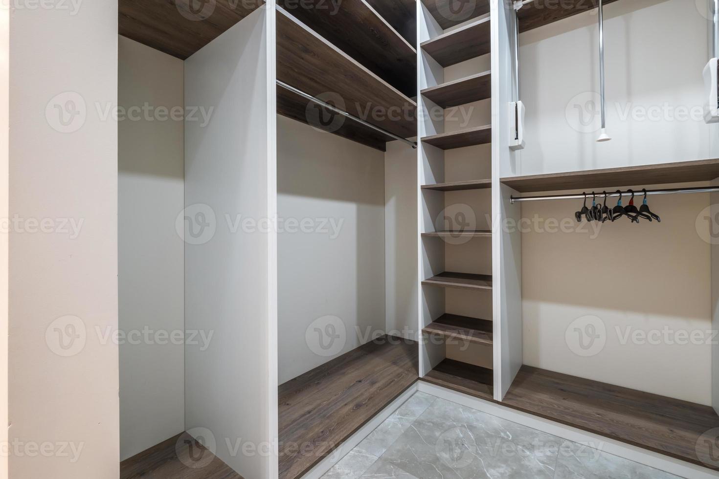 rows of shelves and clothes hangers in the wardrobe. empty big wardrobe room in modern apartment or hotel photo