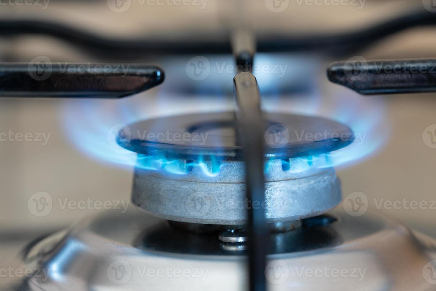 Close-up of a gas stove with gas pouring out and burning. The oven is on. The flame glows blue. photo