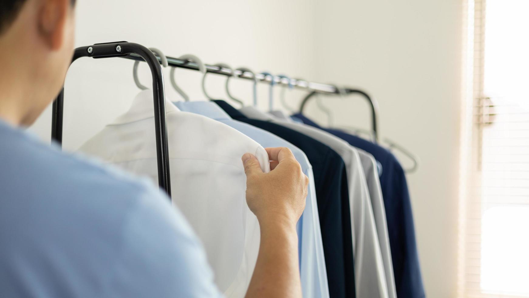 el hombre está eligiendo camisa en el cuarto de ropa en casa. foto