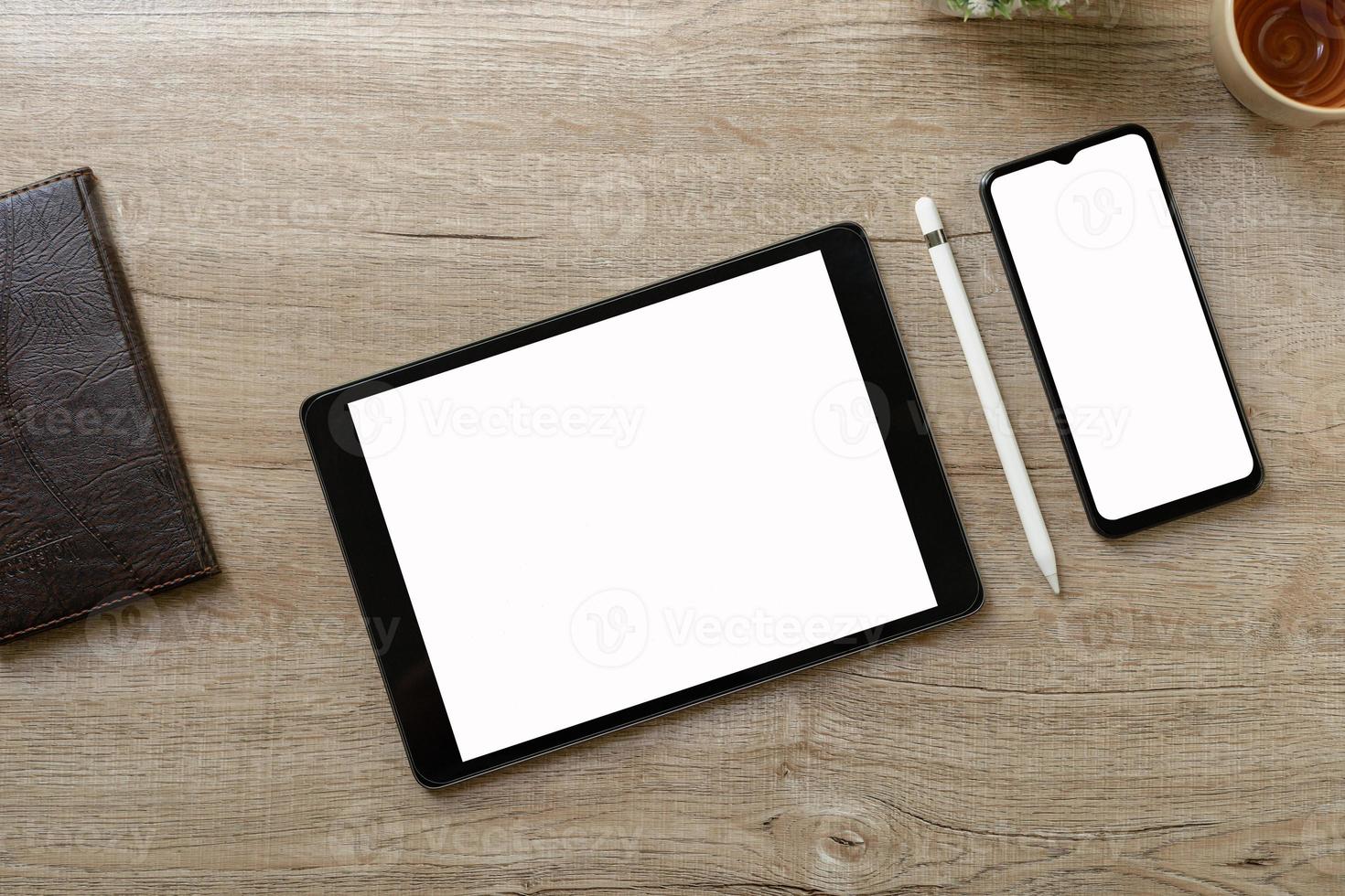 Black tablet with white blank screen is on top of brown paper with supplies. Top view, flat lay. photo