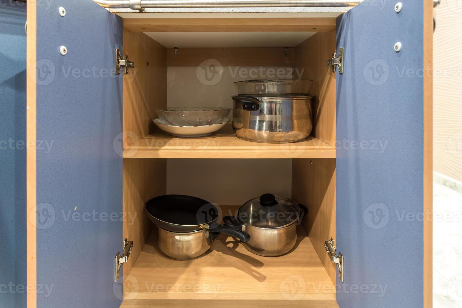 set of plates, cups, knives, forks and wine glasses on the shelf in the kitchen cabinet photo